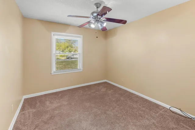 an empty room with a window and a chandelier fan