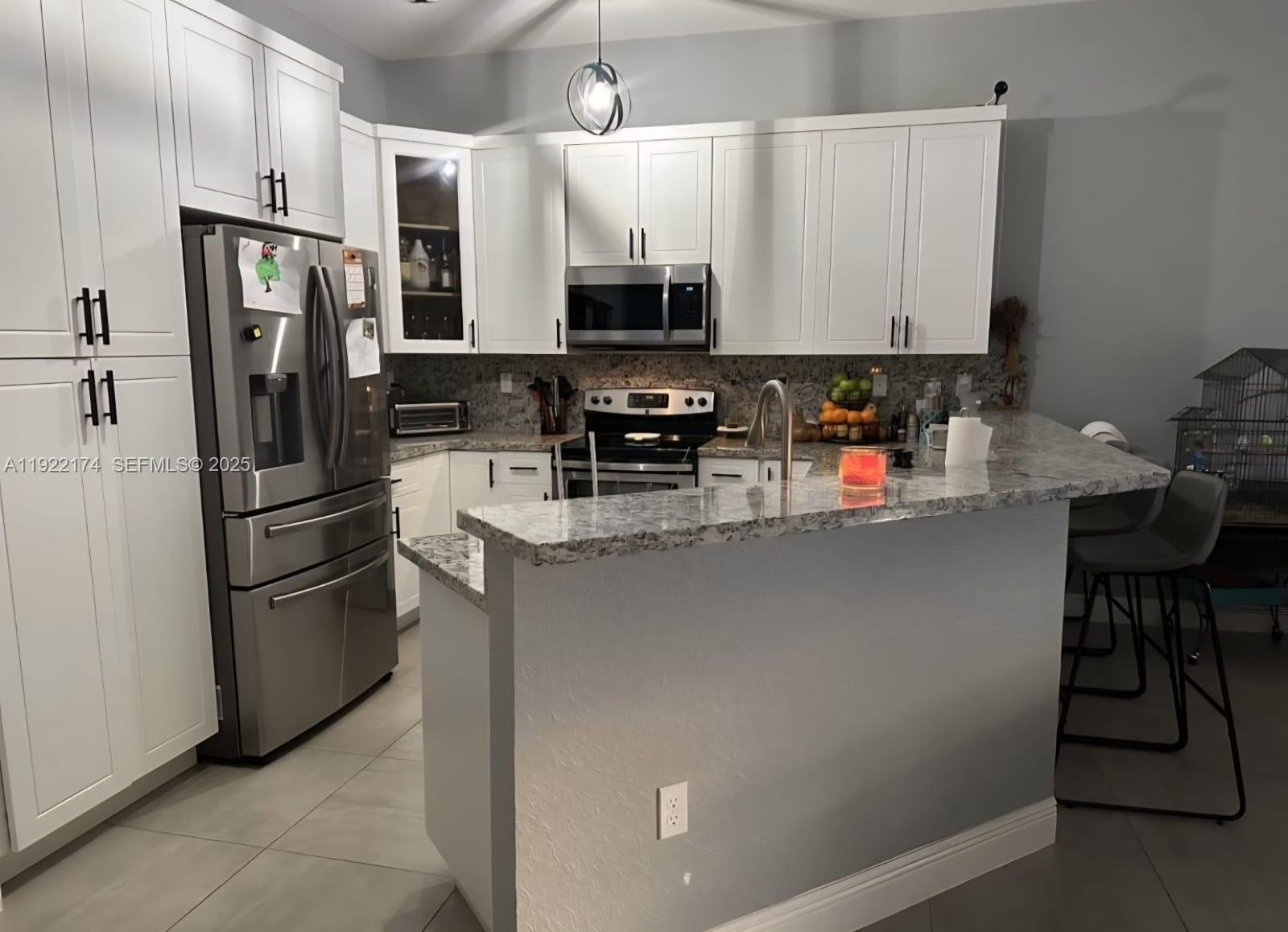 27862 Southwest 134th Court Homestead, FL 33033 - Photo 3 of 14 a kitchen with stainless steel appliances granite countertop a refrigerator and a stove top oven