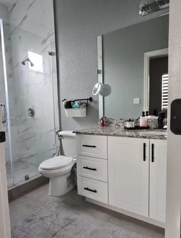a bathroom with a double vanity sink a toilet and a shower