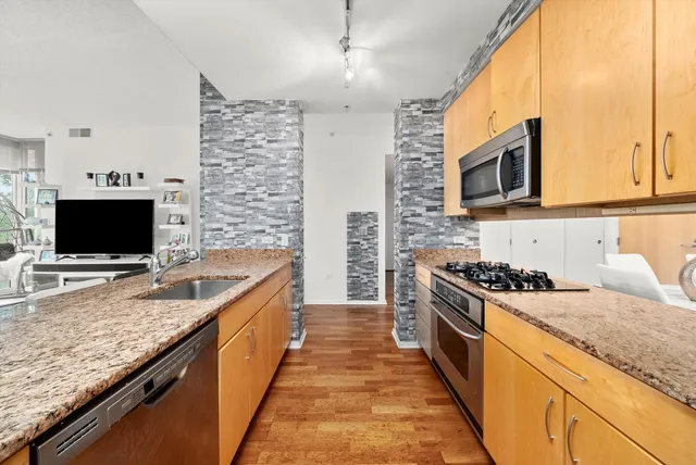 a kitchen with granite countertop kitchen island stainless steel appliances a stove sink and microwave