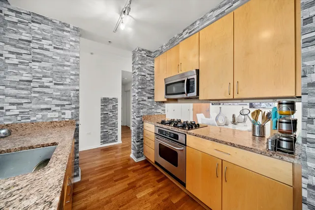 a kitchen with stainless steel appliances granite countertop a stove a sink and a microwave