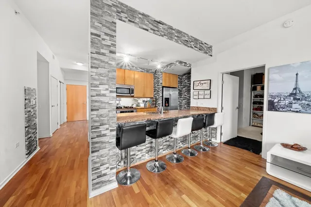 a kitchen with stainless steel appliances kitchen island granite countertop a sink refrigerator and cabinets