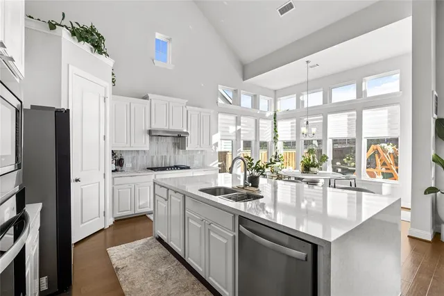 a kitchen with stainless steel appliances a table chairs and a refrigerator