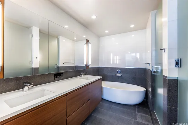 a bathroom with a bathtub a double vanity sink and mirror
