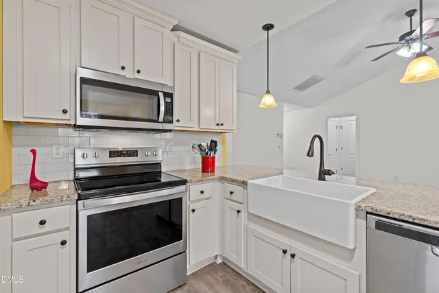 a kitchen with white cabinets and appliances