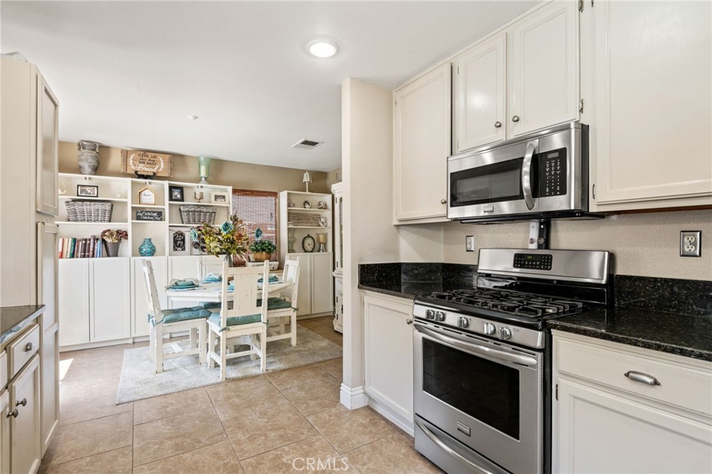 7615 Canberra Way Riverside, CA 92508 - Photo 11 of 37 a kitchen with stainless steel appliances a stove a microwave and chairs