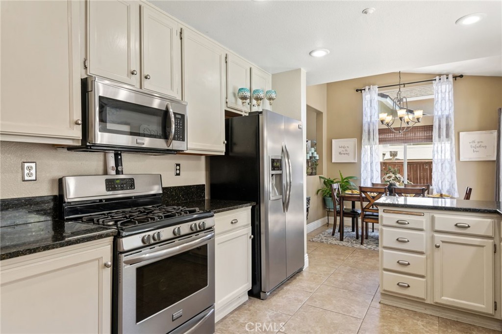 7615 Canberra Way Riverside, CA 92508 - Photo 9 of 37 a kitchen with granite countertop a refrigerator stove and microwave