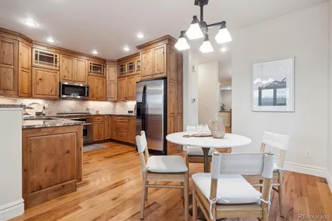a kitchen with stainless steel appliances a dining table chairs refrigerator and sink