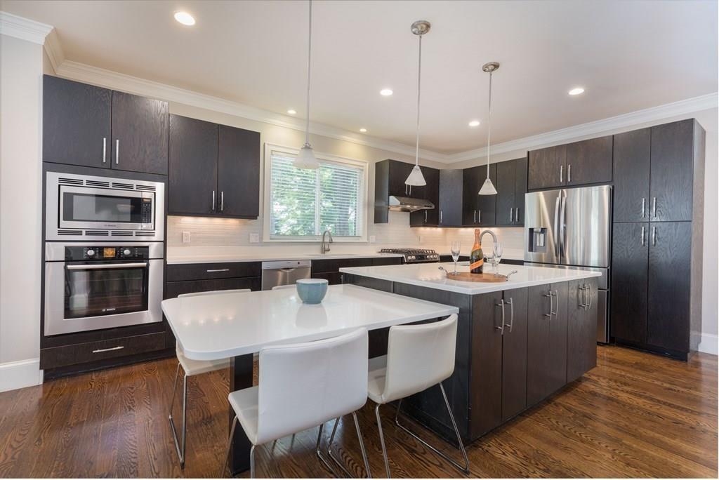 45 Village Circle Newton, MA 02459 - Photo 6 of 18 a kitchen with stainless steel appliances granite countertop a sink a stove a refrigerator with a dining table and chairs