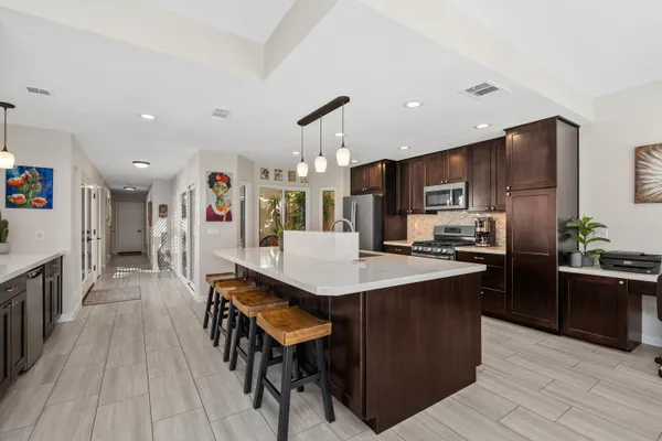 a kitchen with stainless steel appliances kitchen island granite countertop a table chairs and a refrigerator