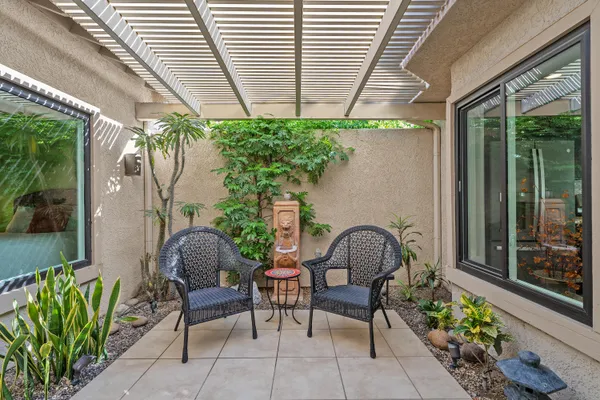 a backyard of a house with table and chairs and potted plants