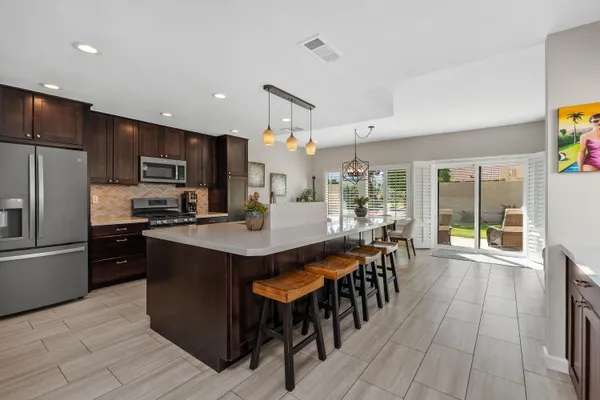 a kitchen with stainless steel appliances kitchen island granite countertop a table chairs and a refrigerator