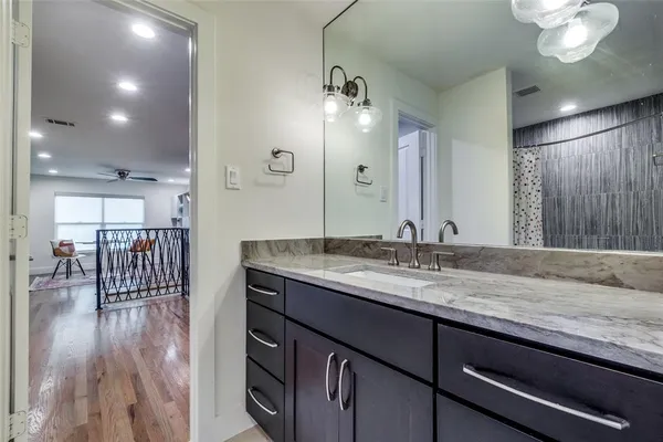 a bathroom with a granite countertop sink a mirror and a shower