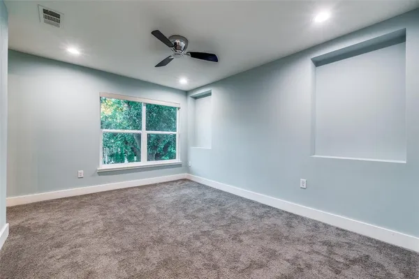 an empty room with windows and ceiling fan