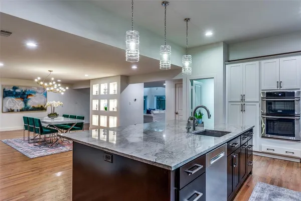 a kitchen with stainless steel appliances granite countertop a sink a stove and a wooden floors