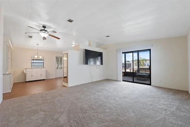 an empty room with chandelier fan and windows