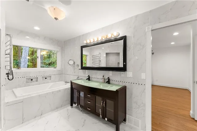 a bathroom with a double vanity sink a mirror and bathtub