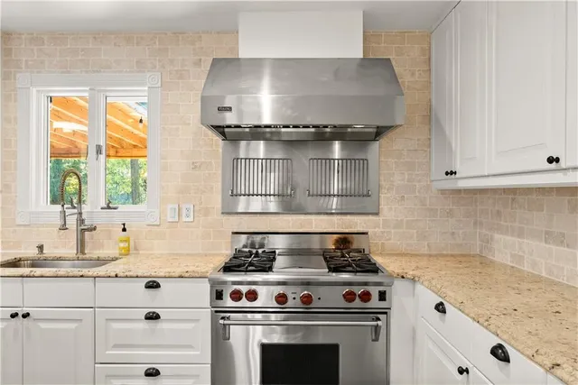 a kitchen with stainless steel appliances granite countertop a stove and a white cabinet