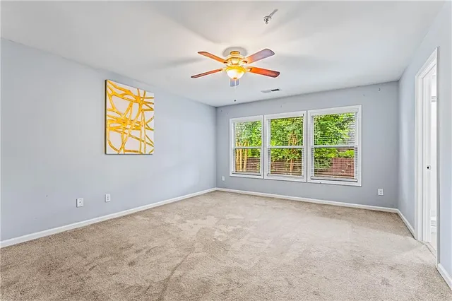 an empty room with windows and chandelier fan