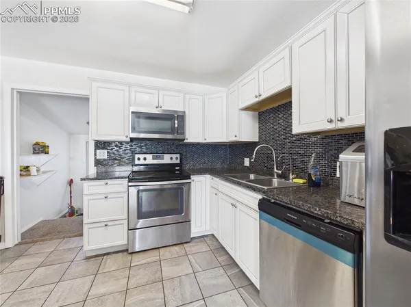 a kitchen with granite countertop a stove sink and cabinets