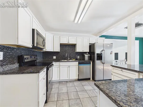 a kitchen with stainless steel appliances granite countertop a stove a sink and a microwave