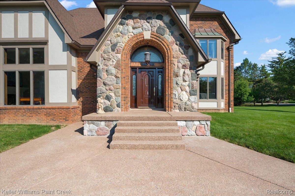 69069 Campground Road Romeo, MI 48065 - Photo 3 of 78 Stone and brick facade featuring a grand arched entry with a decorative wood door and transom window