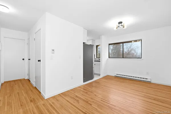 a view of empty room with wooden floor and window