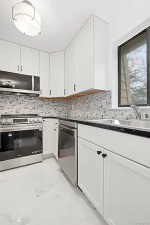 a kitchen with granite countertop white cabinets and white stainless steel appliances