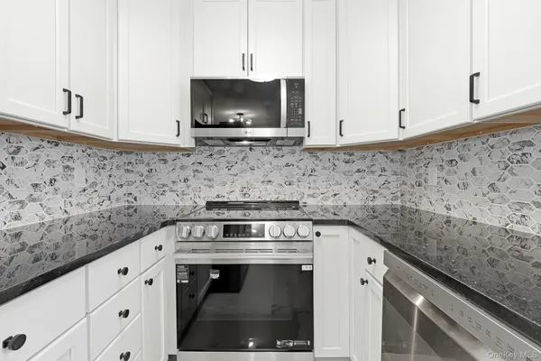 a kitchen with granite countertop white cabinets stainless steel appliances and a sink