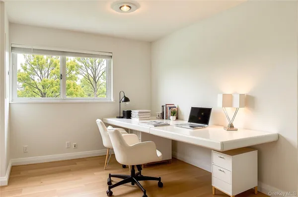a view of a workspace with furniture and a window