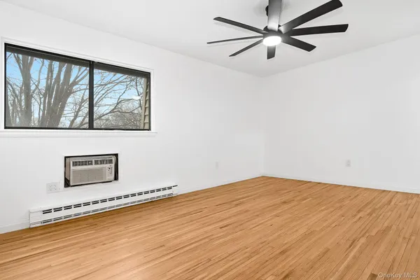 a view of an empty room with a window and wooden floor