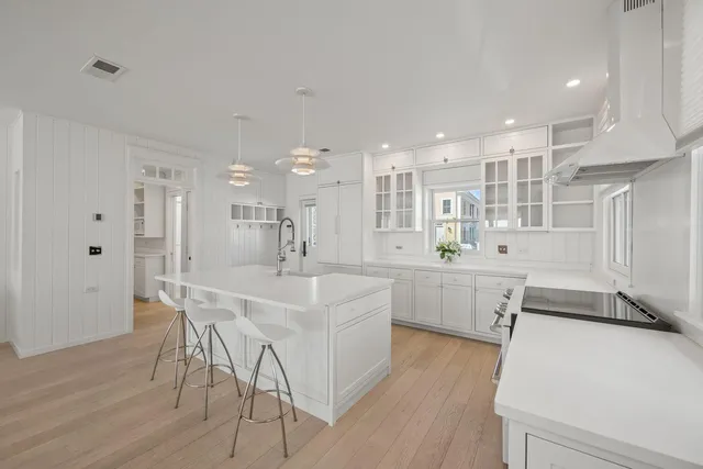 a large white kitchen with wooden floor and stainless steel appliances