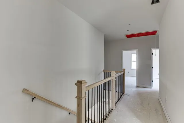 a view of an empty room with window and hardwood floor
