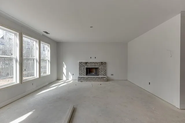 an empty room with a fireplace and large windows