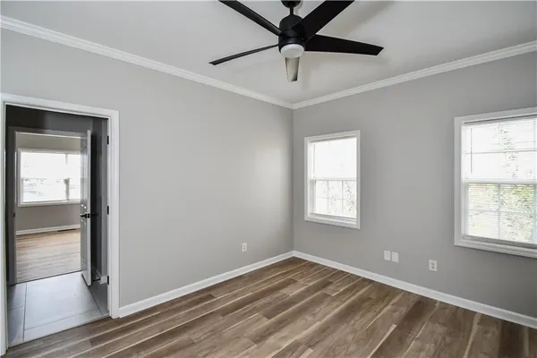 a view of empty room with wooden floor and fan