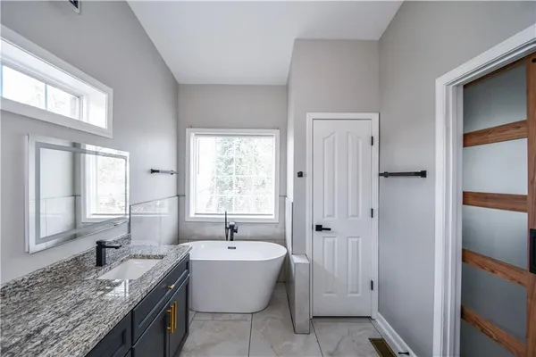 a bathroom with a granite countertop sink a mirror and shower