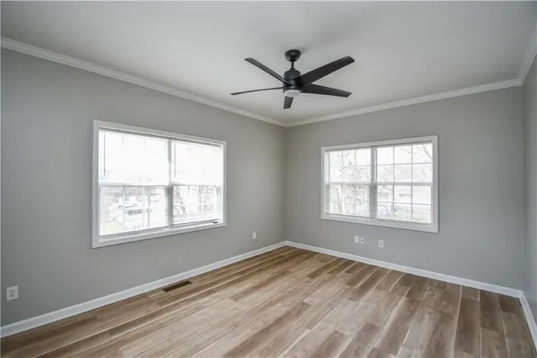 a view of an empty room with a window and wooden floor