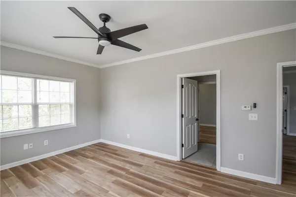 a view of empty room with wooden floor and ceiling fan