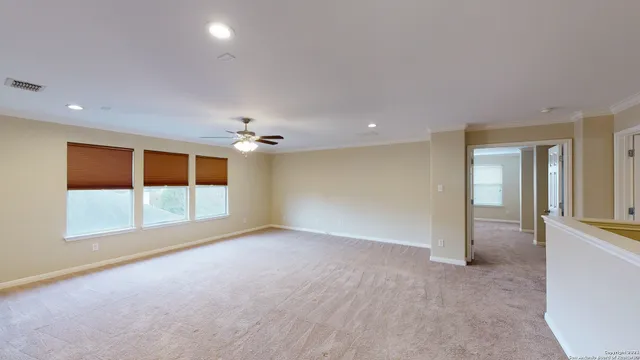 an empty room with windows and chandelier fan