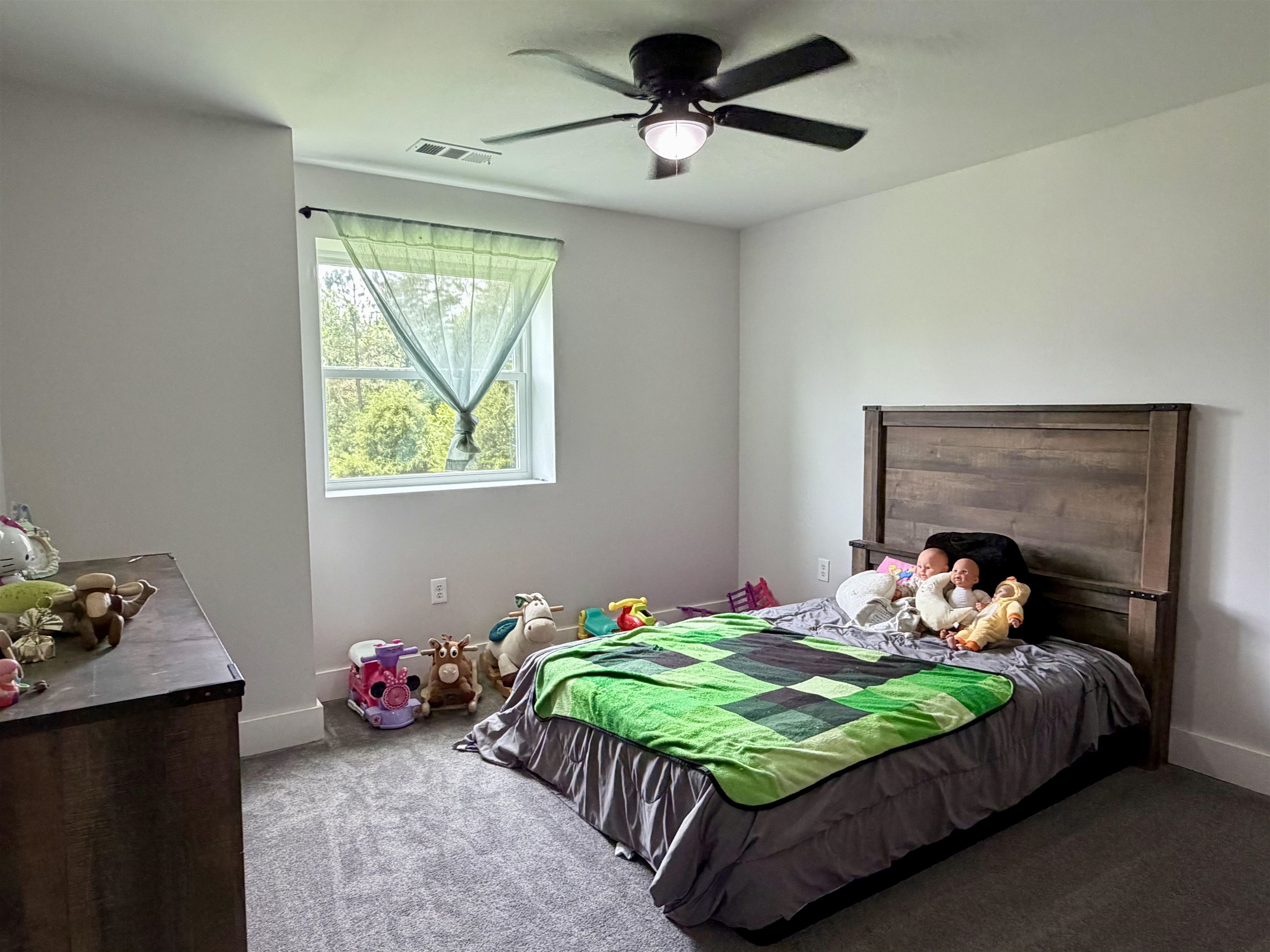 3670 Peavine Road Middleton, TN 38052 - Photo 26 of 36 Bright room featuring a window with exterior tree line, ceiling fan with integrated lighting, gray walls, and carpet flooring
