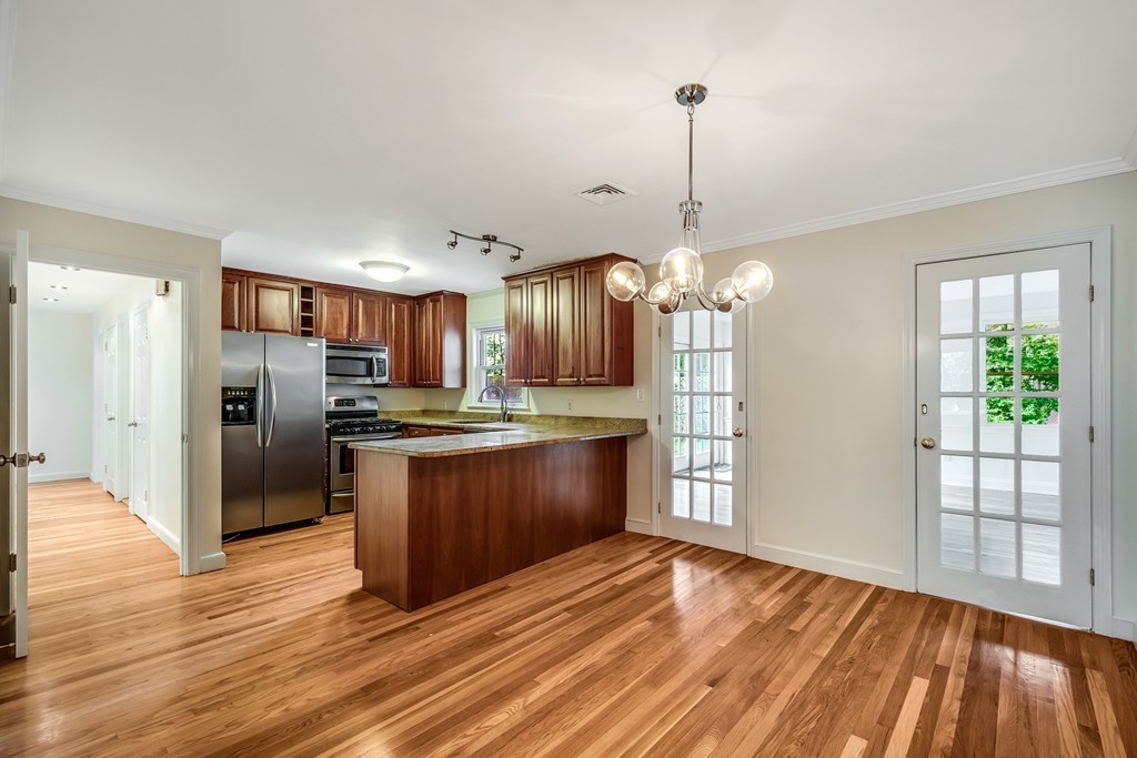 43 Kendall Road Newton, MA 02459 - Photo 6 of 22 a kitchen with stainless steel appliances granite countertop a refrigerator a sink dishwasher a stove and a dining table with wooden floor