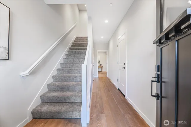 a view of staircase with lots of frames on wall and wooden floor