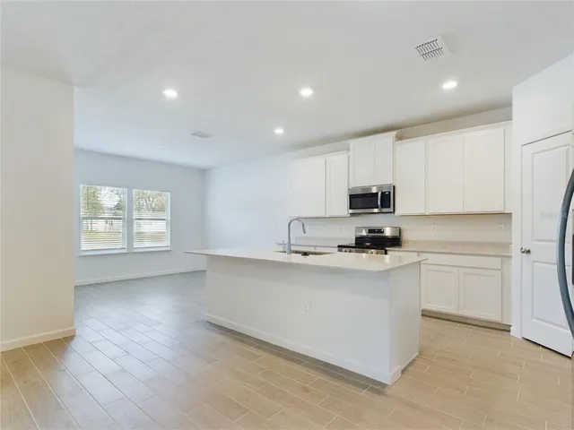 a kitchen with stainless steel appliances a refrigerator sink and white cabinets
