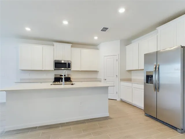 a kitchen with stainless steel appliances a refrigerator sink and white cabinets