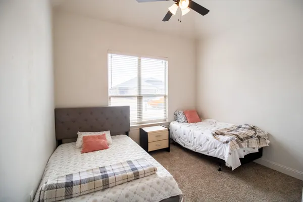 a bedroom with two beds lamp and a window