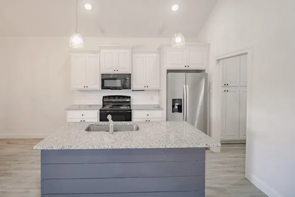 a kitchen with kitchen island a refrigerator and a stove top oven