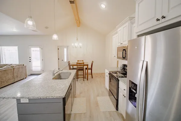 a kitchen with stainless steel appliances granite countertop a refrigerator a stove a sink a dining table and chairs