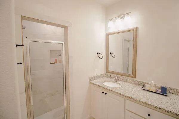 a bathroom with a granite countertop sink a mirror and a shower