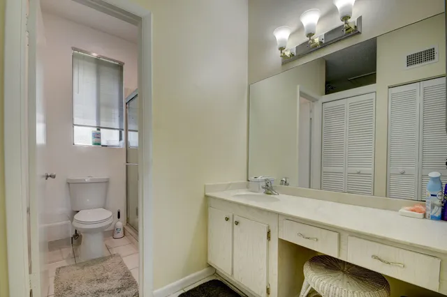 a spacious bathroom with a double vanity sink a toilet and a mirror