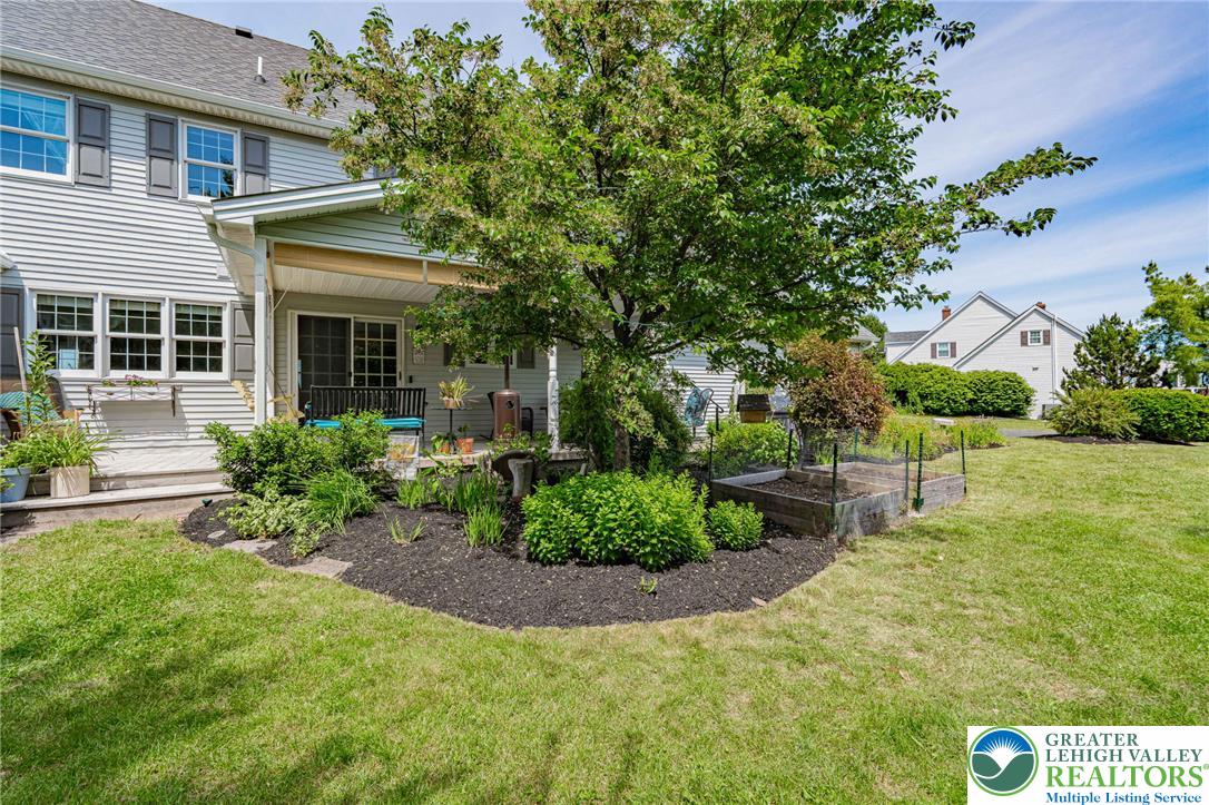 4542 Springfield Drive Coplay, PA 18037 - Photo 66 of 89 A verdant backyard retreat featuring a mature shade tree, lush garden beds, and an inviting patio with sliding glass doors.